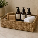 A low rectangular woven tray for arranging guest toiletries, folded towels and welcome essentials.