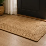 A rectangular jute floor mat with a braided surface and a defined border for an understated entrance setting.