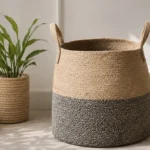 A rounded woven storage basket with an inward-curving rim, loop handles and contrasting natural and grey sections.