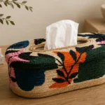 A rectangular woven tissue cover with colourful floral motifs and a central opening at the top.